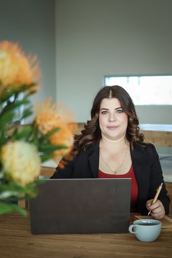 Carnaby Settlements - Shelley at desk with laptop and flowers in foreground Carnaby Settlements - Shelley at desk with laptop and flowers in foreground